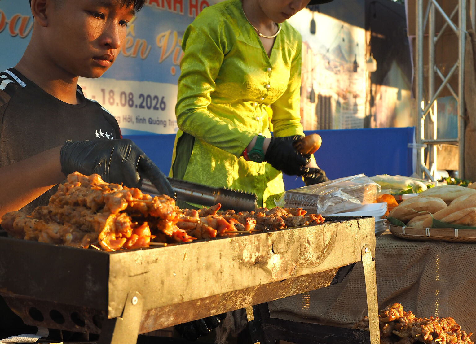 Hai người đang trở món nướng trên bếp than tại gian hàng ở Quảng Trị