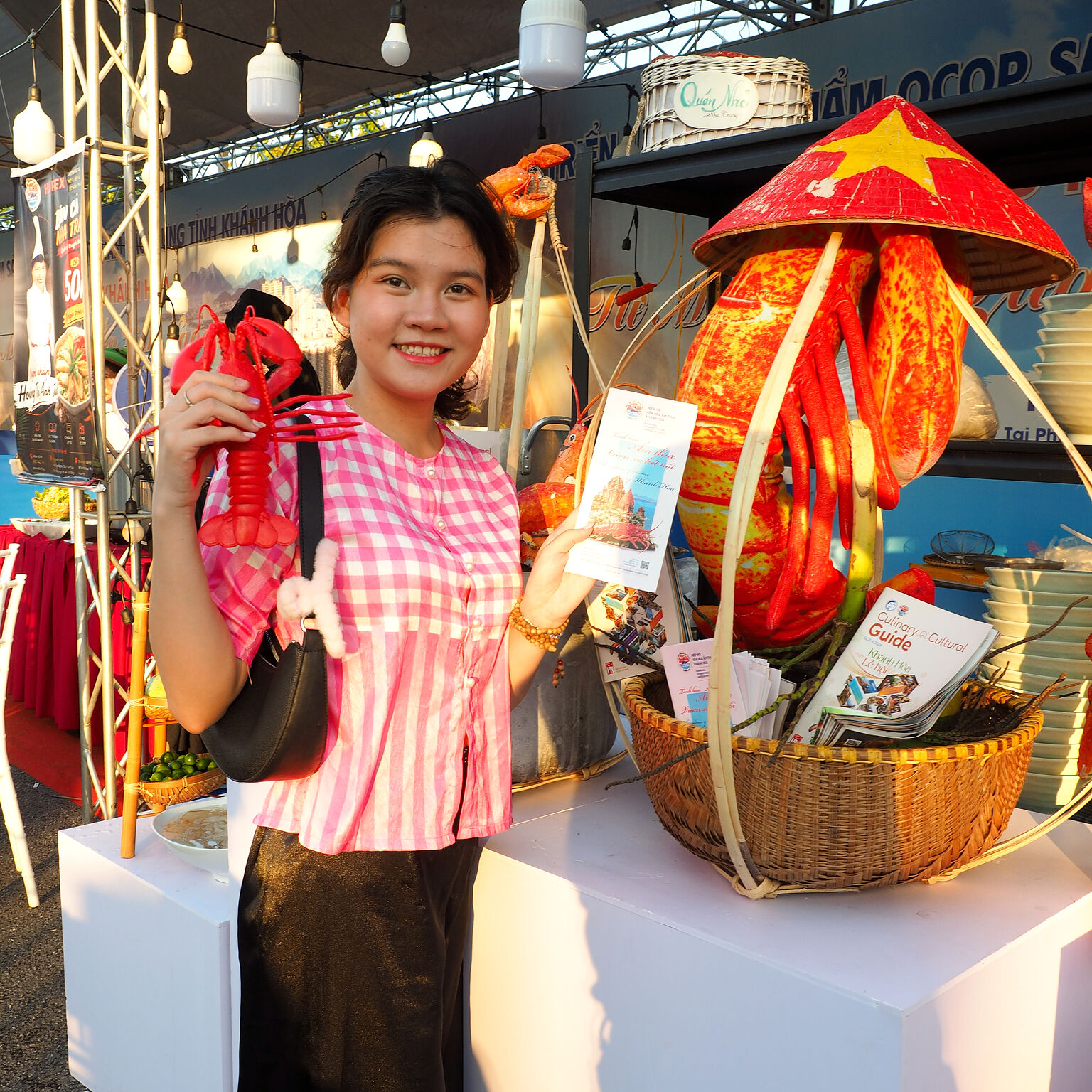 Khách tham quan cầm phần quà và brochure bên giỏ quà tại gian hàng KCCA