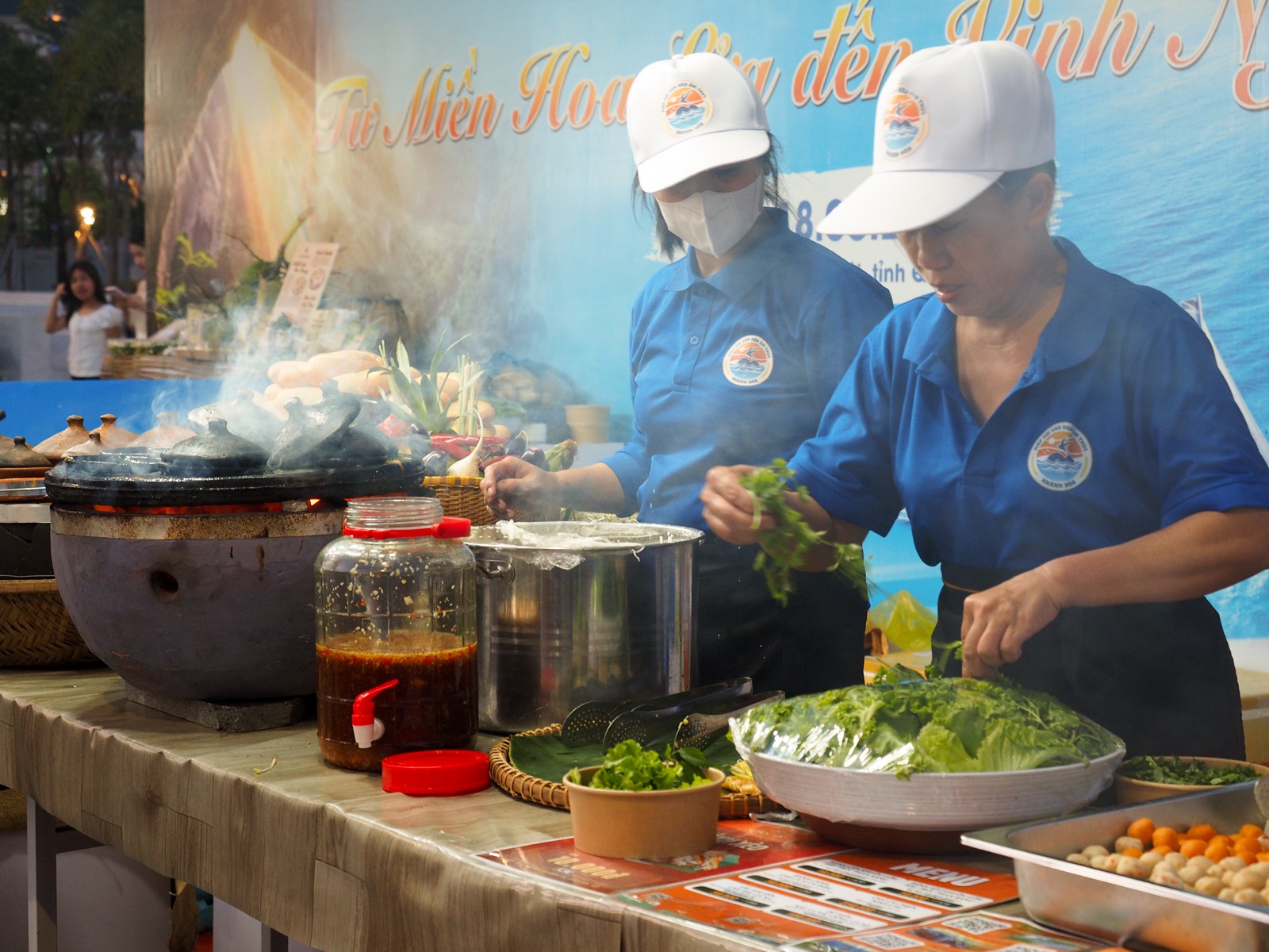 Hai người của Hiệp hội Văn hóa Ẩm thực Khánh Hòa chuẩn bị món bên bếp than và khuôn đất nung