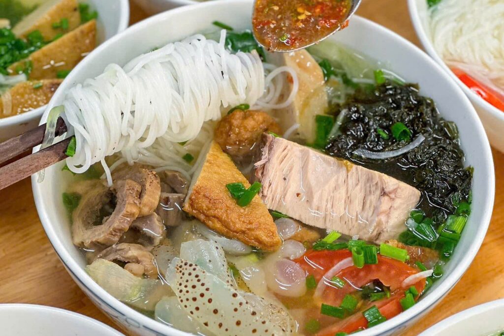 Sợi bún được gắp lên từ một tô bún cá với chả cá và cá
